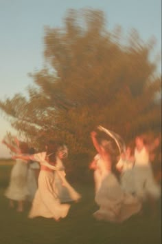 blurry photograph of women in white dresses playing with a frisbee