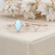 an opal and diamond ring sitting on top of a white box with flowers in the background