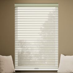 two white pillows sitting on top of a couch next to a window covered in blinds