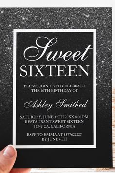 a hand holding up a black and white birthday party card with the words sweet sixteen on it