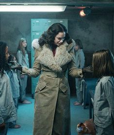 a woman in a trench coat is surrounded by other people