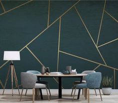 a dining table with two chairs and a lamp on it in front of a green wall