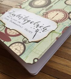 a close up of a book on a wooden table with a clock and name tag