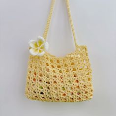 a crocheted purse with a flower on the front and side, hanging from a hook