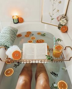 a person sitting in a bathtub with an open book and orange slices on the edge