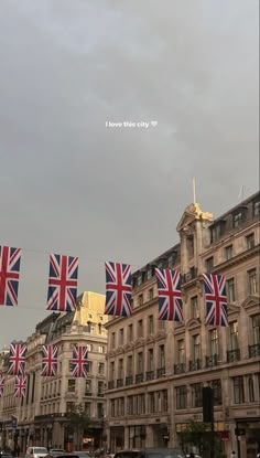 several british flags are flying in the air over a street lined with buildings and cars