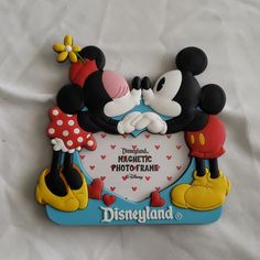 mickey and minnie kissing in front of a photo frame with the words disneyland written on it