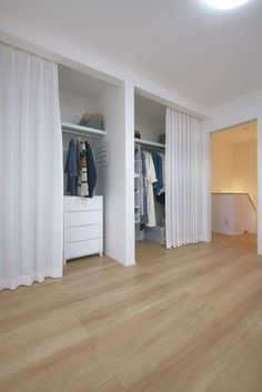 an open closet with white curtains and clothes