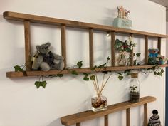 three wooden shelves with plants and stuffed animals on them, one shelf is holding two vases