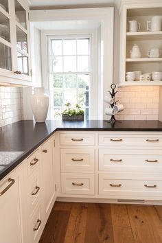 a kitchen with white cabinets and black counter tops, along with wooden floors is shown