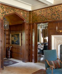 an ornately decorated living room with wood paneling and blue chair in front of the fireplace