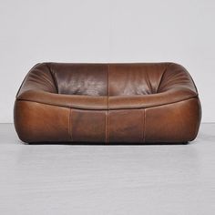 a brown leather couch sitting on top of a white floor