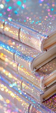 three books are stacked on top of each other with colorful sparkles all over them