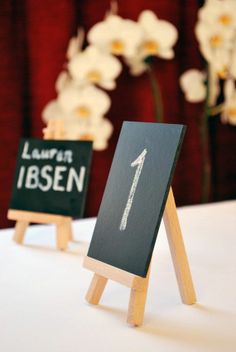 two wooden easels with chalkboard signs on them sitting on a white table cloth