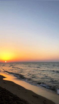 the sun is setting over the ocean on the beach