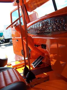 the interior of an orange truck with chrome trims and gauges on it's dashboard