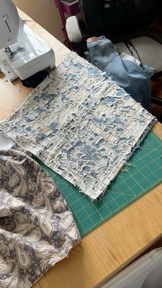 several pieces of fabric sitting on top of a wooden table next to a sewing machine