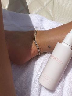 a person laying on a towel next to a bottle of sunscreen