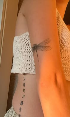 a woman with a dragonfly tattoo on her stomach and the words written in chinese