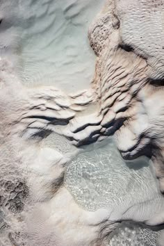 an aerial view of some water and rocks in the desert, with small patches of snow on the ground