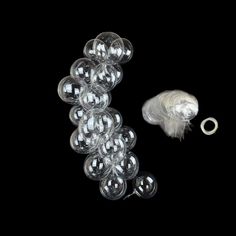 an assortment of clear glass objects on a black background, including one ring and several balls