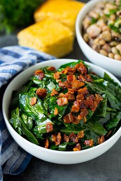 two white bowls filled with spinach and bacon on top of a blue checkered table cloth