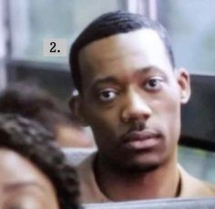 a man is looking at the camera while sitting on a bus with another person behind him