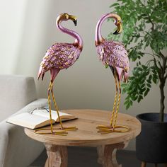 two pink flamingos standing on top of a wooden table