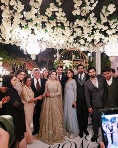 a group of people standing next to each other in front of a chandelier