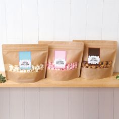 three brown paper bags filled with different types of food on top of a wooden shelf