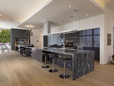 a large kitchen with marble counter tops and stainless steel appliances, along with hardwood floors