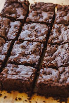 brownies cut into squares sitting on top of a wooden cutting board with chocolate chips