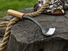 a metal spoon sitting on top of a piece of wood next to a tree stump