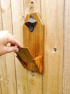 a person is holding a piece of wood in front of a wooden wall with a clock on it