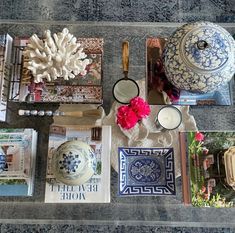 a table topped with plates and vases filled with flowers on top of a rug