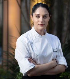 a woman wearing a chef's coat standing with her arms crossed