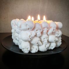 there is a white cake with skulls on it and three candles in the middle of it