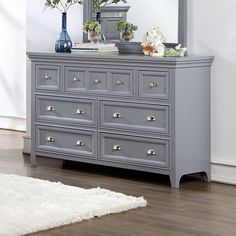 a gray dresser with flowers and a mirror