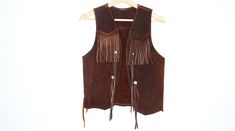 "Vintage 70s vest in brown suede leather with fringe trim. Open front with fringe on shoulder. Condition: Good vintage, has had some repairs on shoulder. Best fits women's: XS to S Material: Suede leather MEASUREMENTS Taken from seam to seam while the garment is lying flat. Double the armpit, waist, and hips Length from Top: 20\" Armpit to Armpit: 17\" Waist: 18\" Shoulder to Shoulder: 17.5\"" Brown Fringe Vest For Fall, Brown Fringe Vest For Festival, Leather Fringe Vest, Western Fringe Vest, Bohemian Brown Vest With Fringe, Festival Fringe Brown Vest, Bohemian Brown Fringe Vest, Brown Bohemian Vest With Fringe, Fitted Vintage Leather Vest