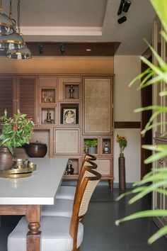 a dining room table with chairs and vases on it's centerpiece, in front of a built - in bookcase