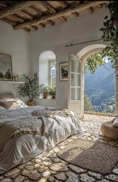 a bedroom with an arched window and stone flooring, overlooking the mountains in italy