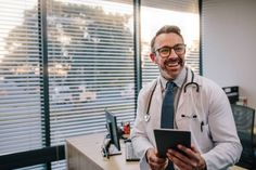 a man in a doctor's coat is holding a tablet