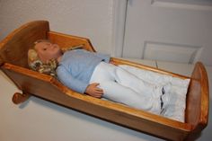 a doll is laying in a wooden cradle