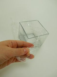 a hand is holding a plastic object on a white surface