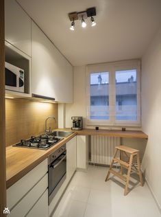 a small kitchen with an oven, stove and stool in it's corner area