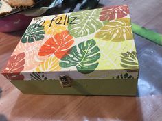 a colorful box sitting on top of a wooden table next to a plate with bread