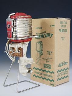 an old fashioned water pump sitting in front of a cardboard box on a white surface