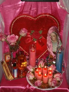 a heart shaped shrine with candles, roses and pictures on the table next to it