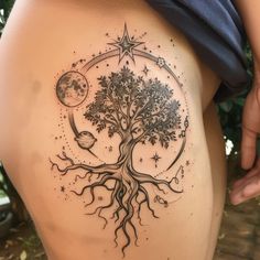 a woman's thigh with a tree and moon tattoo on it