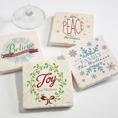 four stone coasters with christmas designs on them and wine glass in the middle one